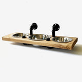 May include: A wooden pet food station with three stainless steel bowls. The bowls are mounted on a wooden shelf with black metal pipes.